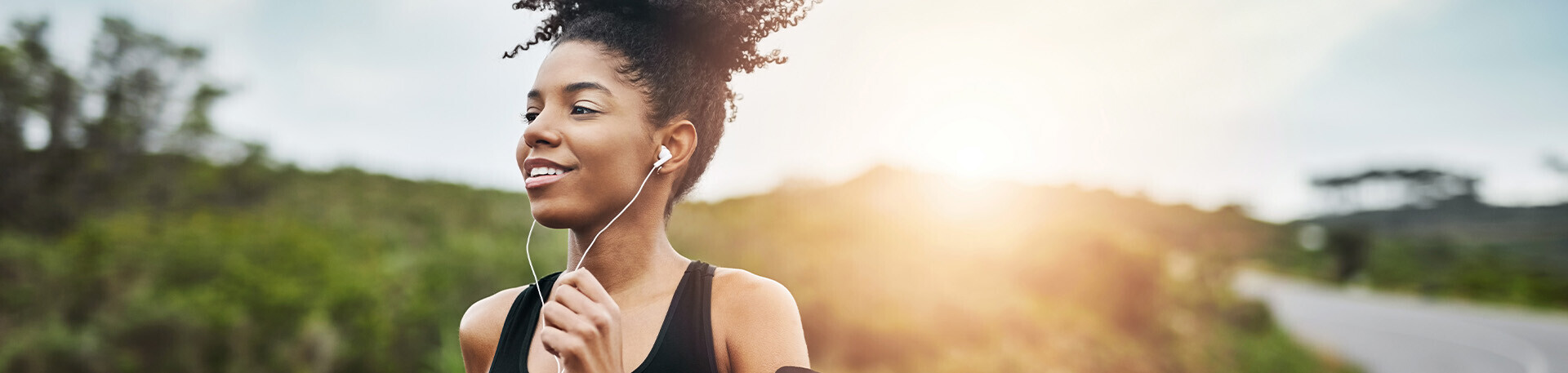 Frau mit Kopfhörern und Sportklamotten rennt auf einer Straße