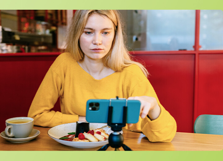 Eine Studentin schaut beim Essen auf ihr Handy