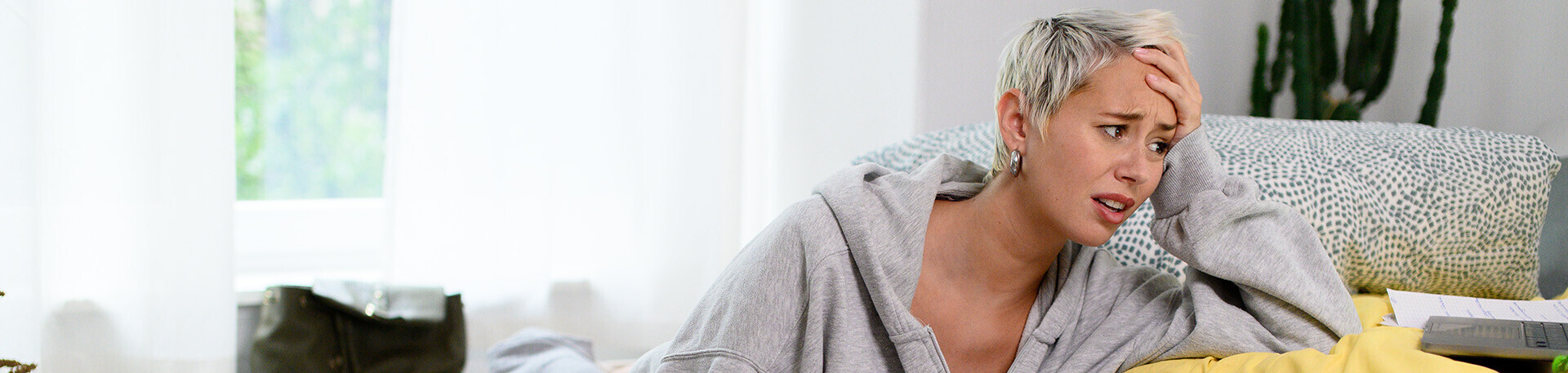 Junge Frau sitzt verzweifelt vor ihrem Unterlagen auf dem Boden