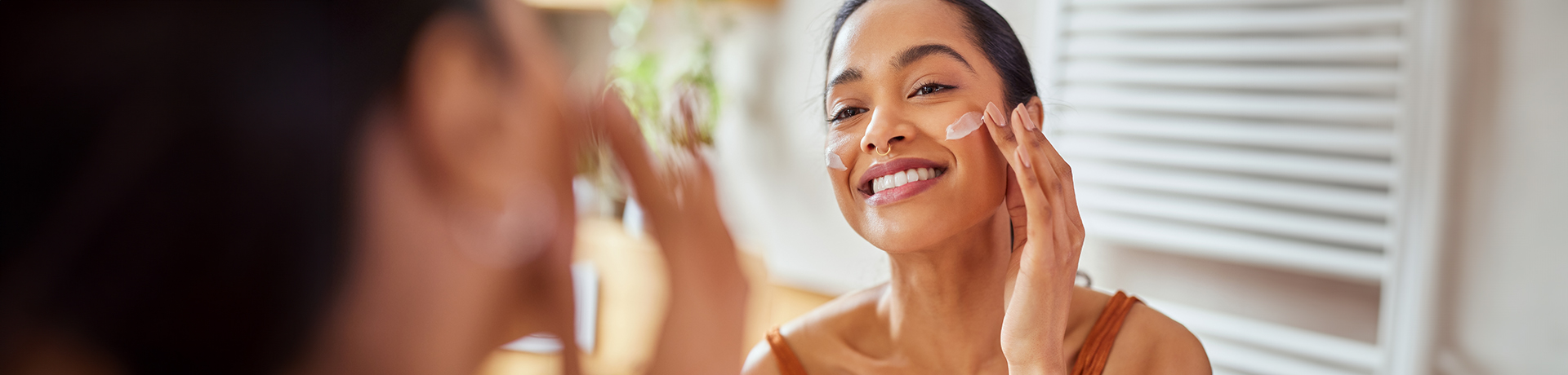 Frau verwendet Gesichtscreme auf ihrer Wange