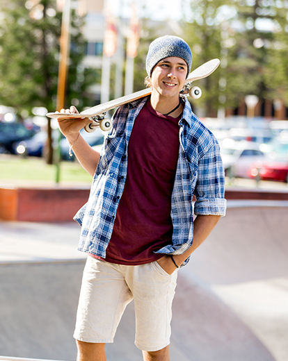 Junger Mann mit Skateboard auf der Schulter