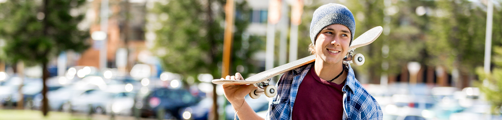 Junger Mann mit Skateboard auf der Schulter