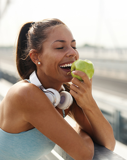 Frau in Sportklamotten beißt in Apfel