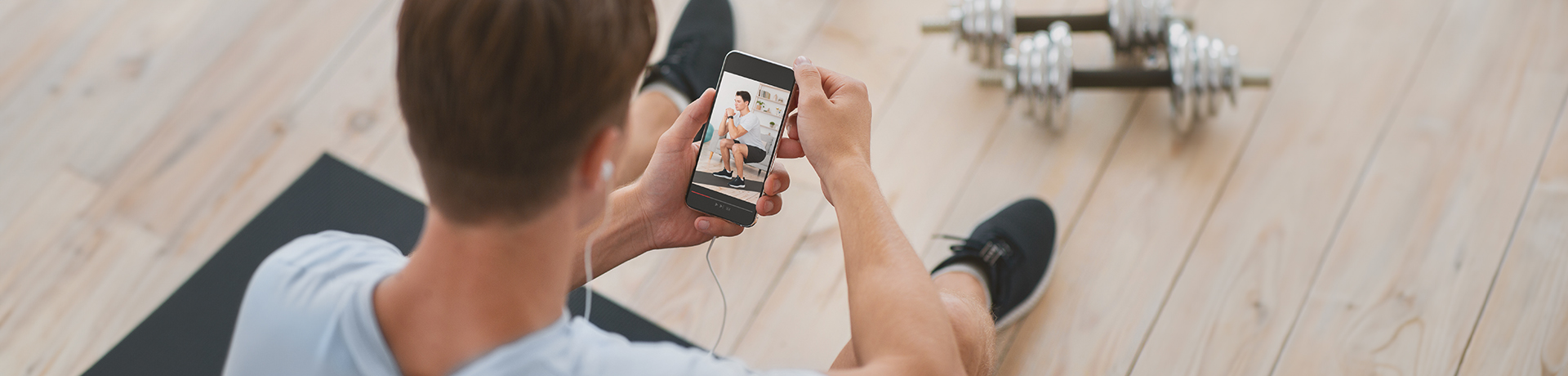 Mann schaut sich ein Workout auf seinem Handy an