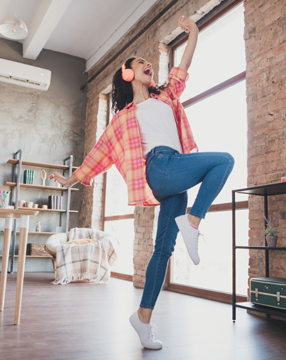 Junge Frau mit Kopfhörern tanzt fröhlich