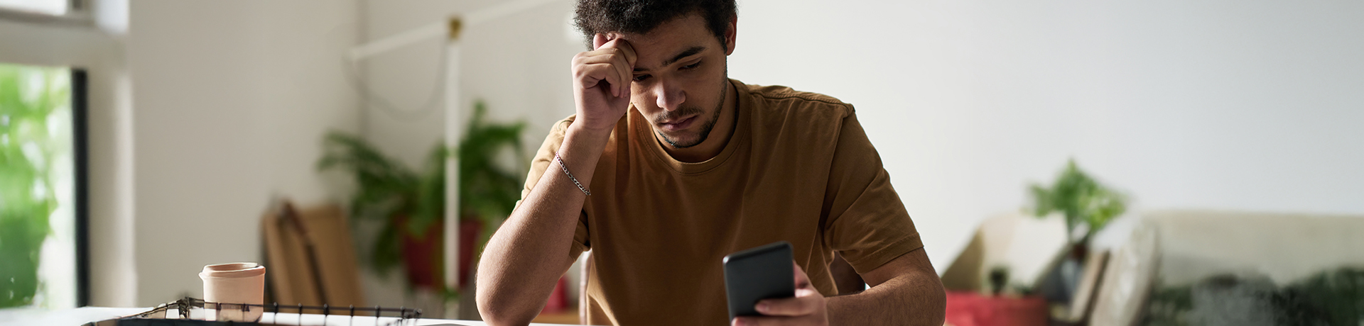 Ein junger Mann schaut unglücklich auf sein Handy. 