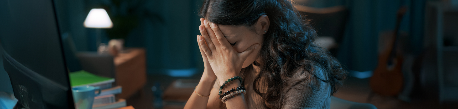 Frau hat das Gesicht in ihre Hände gestützt und sitzt vor ihren Unterlagen