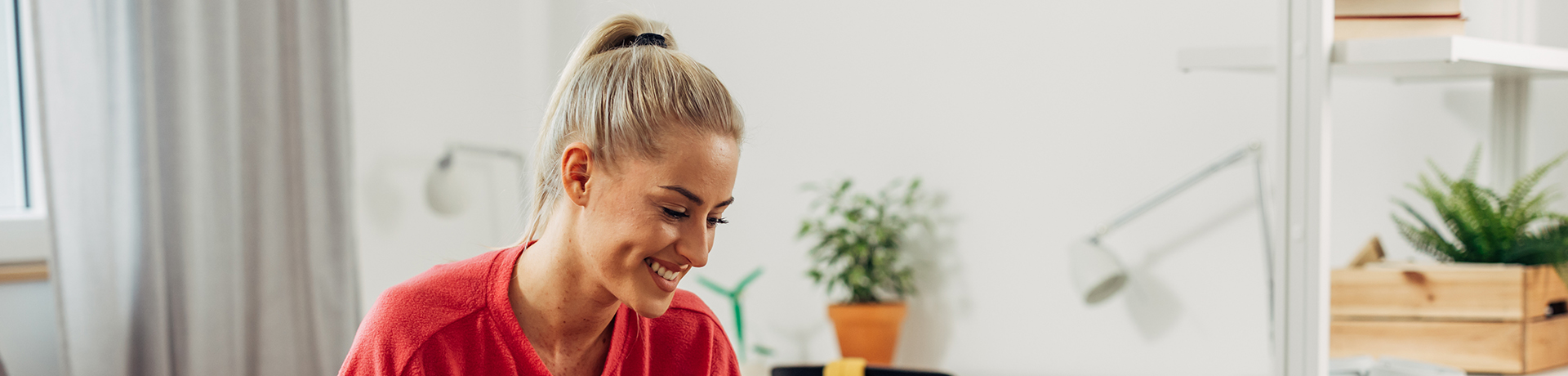 Frau isst Müsli und schaut auf ihren Laptop