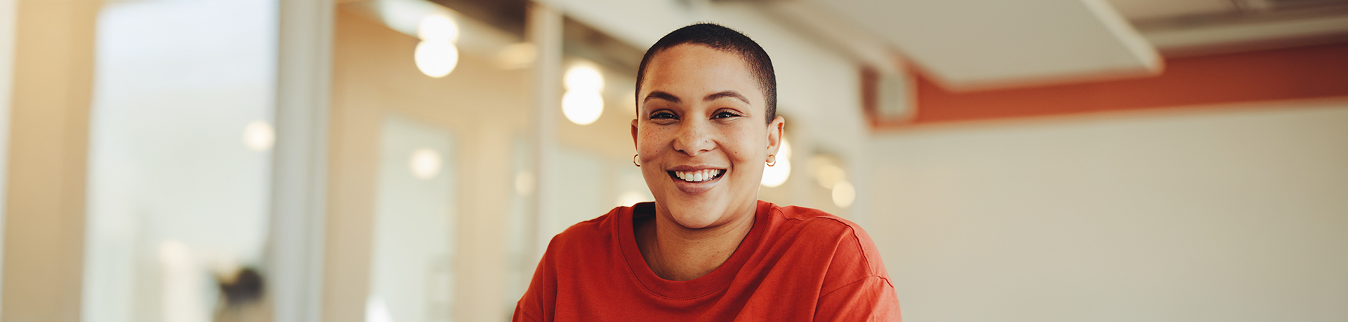 Junge Frau vor einem Buch in einem Klassenraum grinst