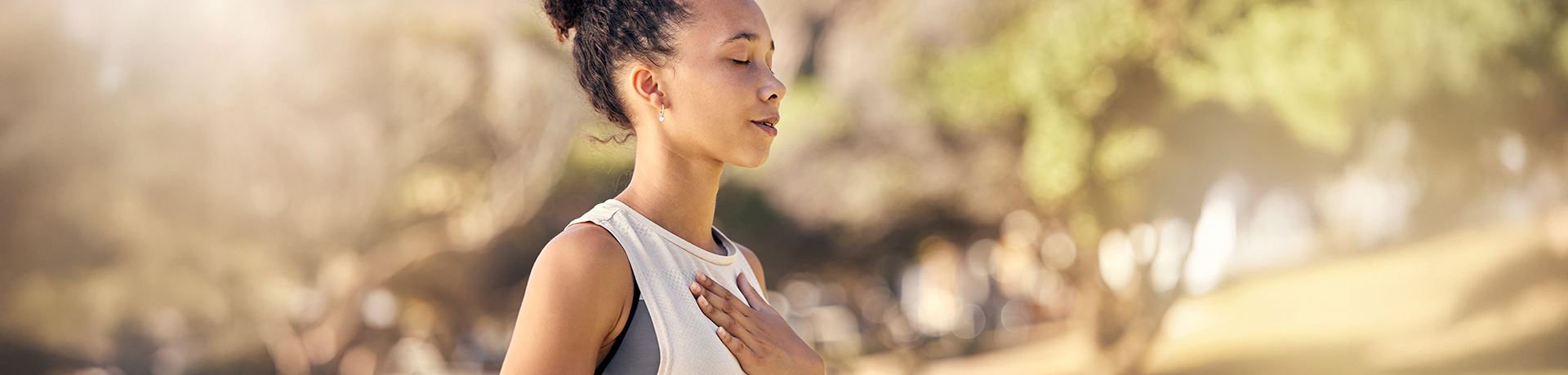 Junge Frau steht mit geschlossenen Augen in der Natur