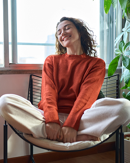 Frau sitzt lächeln im Schneidersitz auf einem Stuhl