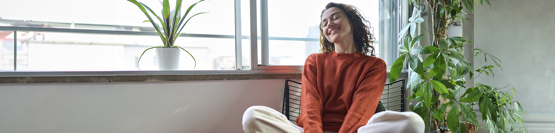 Frau sitzt lächeln im Schneidersitz auf einem Stuhl