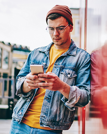 Junger Mann mit Mütze schaut auf sein Handy