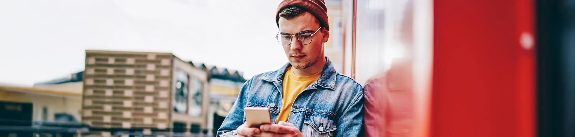 Junger Mann mit Mütze schaut auf sein Handy