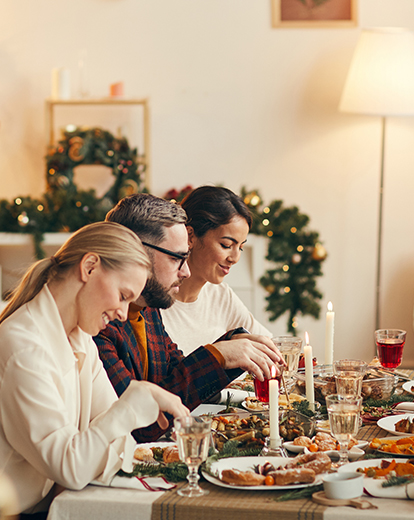 Mehrere Menschen sitzen an Weihnachten an einem Tisch und essen gemeinsam