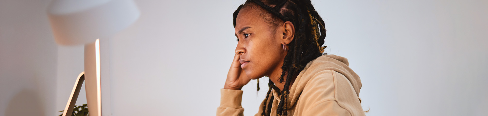 Junge Frau sitzt nachdenklich vor ihrem Laptop.