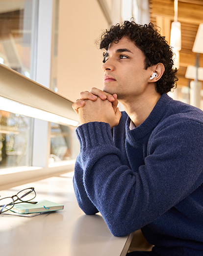 Junger Mann sitzt nachdenklich in der Bibliothek