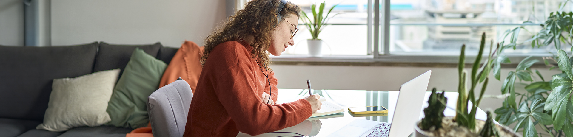 Studentin sitzt am Schreibtisch und schreibt auf ein Papier