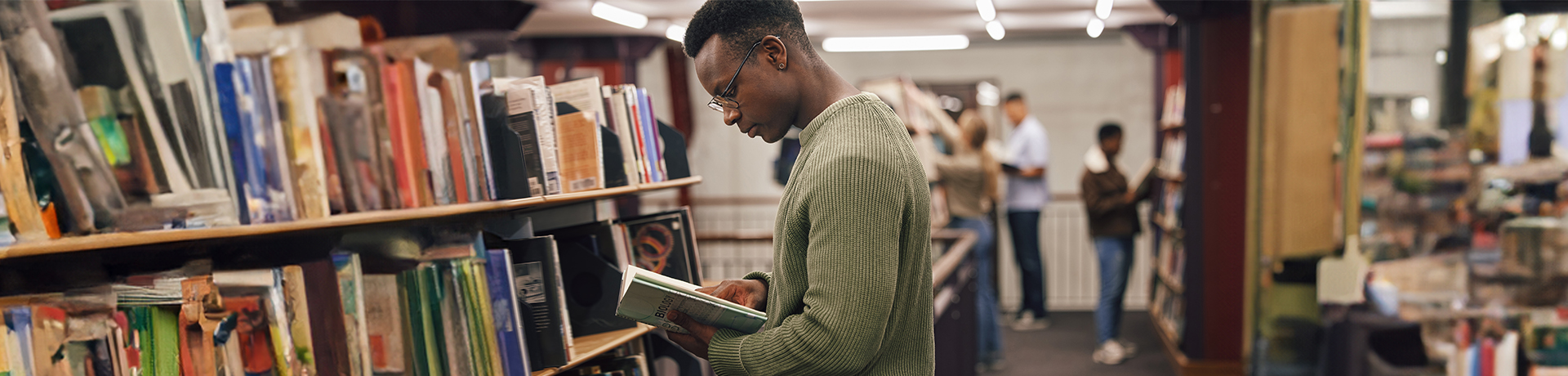 Student ist in Bibliothek über ein Buch gebeugt