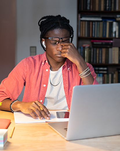Mann sitzt vor Laptop und reibt sich die Augen