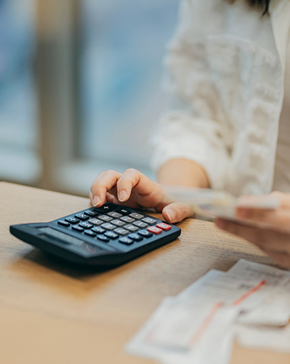 Frau sitzt vor Taschenrechner
