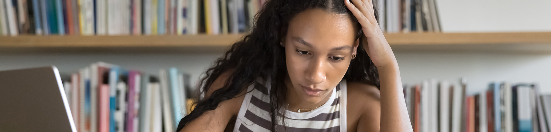 Junge Frau sitzt konzentriert am Schreibtisch und lernt.