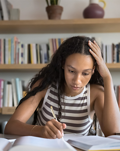 Junge Frau sitzt konzentriert am Schreibtisch und lernt.