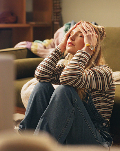 Junge Frau auf dem Boden sitzend, das Gesicht in die Hände gestützt