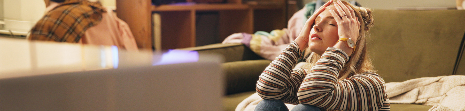 Junge Frau auf dem Boden sitzend, das Gesicht in die Hände gestützt