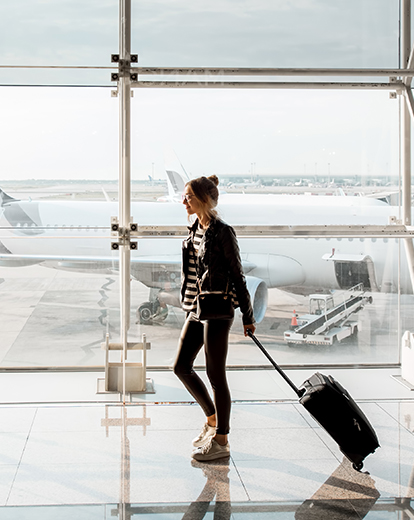 Junge Frau schiebt ihren Koffer durch den Flughafen