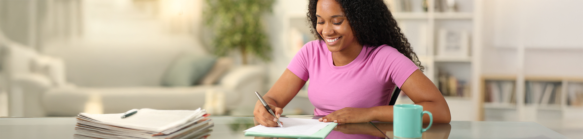 Junge Frau schreibt lächelnd auf ein Blatt Papier