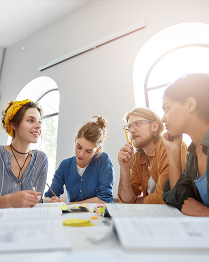 Gruppe an Studenten in einer Gruppenbesprechung um einen Tisch