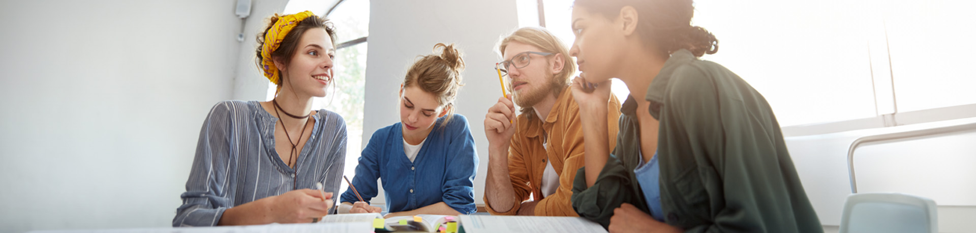 Gruppe an Studenten in einer Gruppenbesprechung um einen Tisch