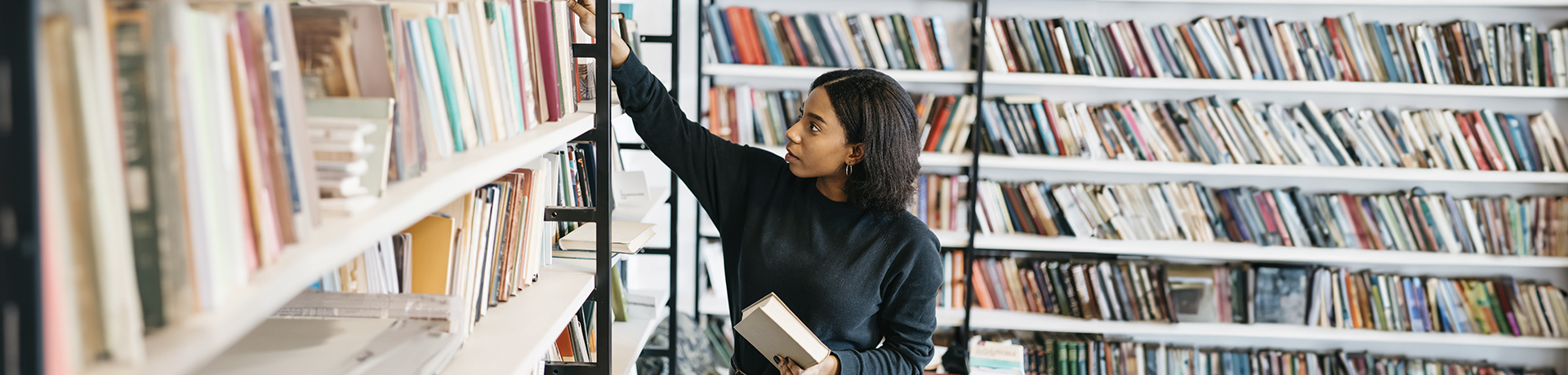 Studentin in einer Bibliothek vor einem Bücherregal