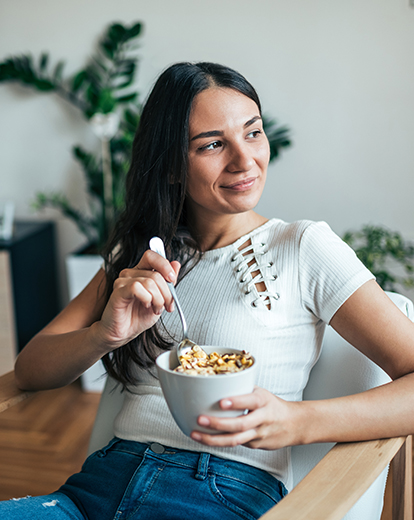 Junge Frau sitzt zufrieden an einem Tisch mit einem Müsli