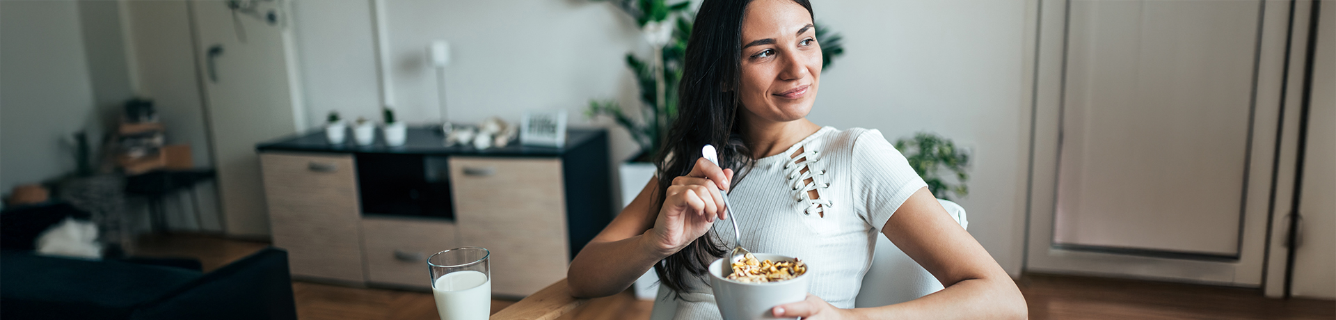 Junge Frau sitzt zufrieden an einem Tisch mit einem Müsli