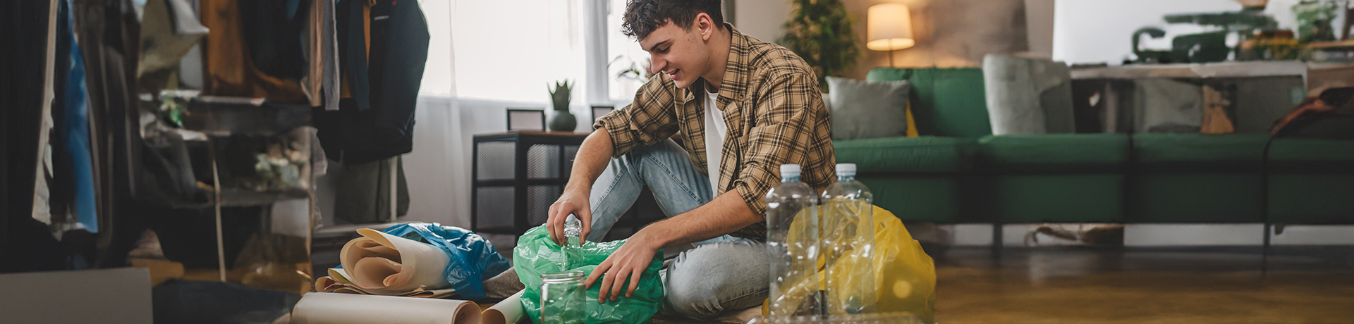 Junger Mann sitzt auf dem Boden und sortiert Müll