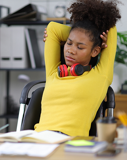 Studentin lehnt sich müde in einem Schreibtischstuhl nach hinten