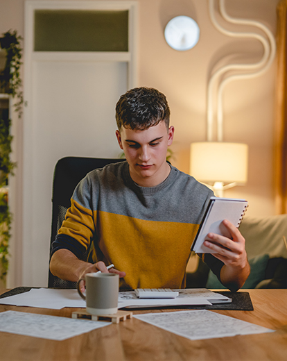 Student sitzt an einem Schreibtisch vor Papieren