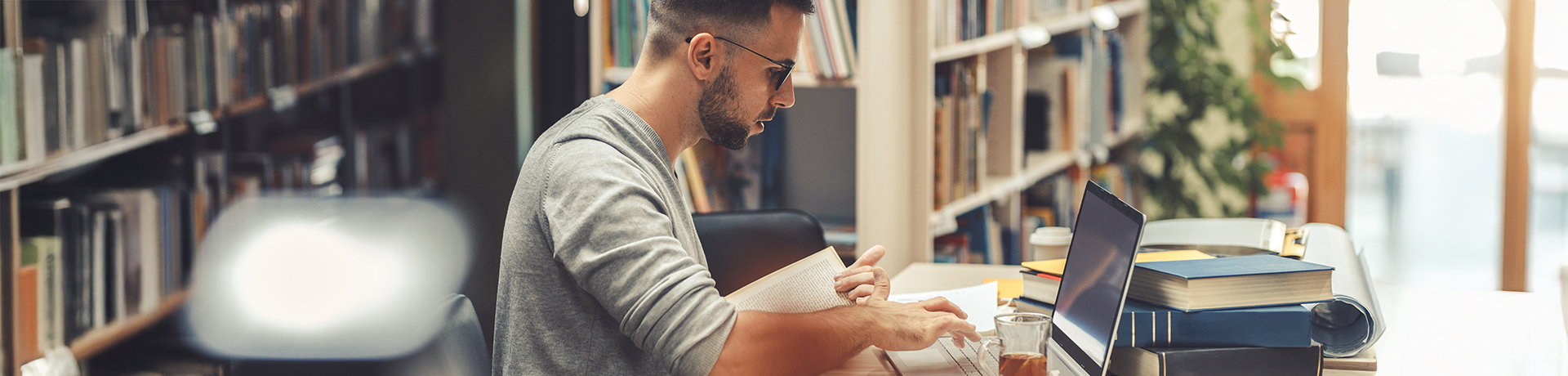 Junger Mann an Tisch in einer Bibliothek