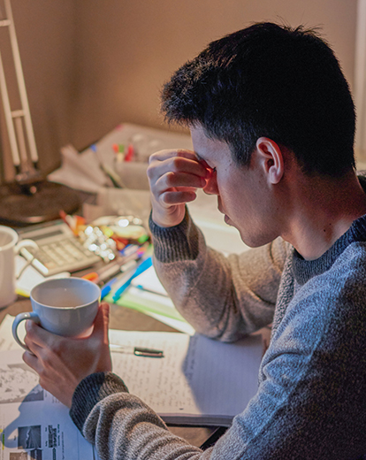 Student hält sich den Kopf beim Lernen am Schreibtisch