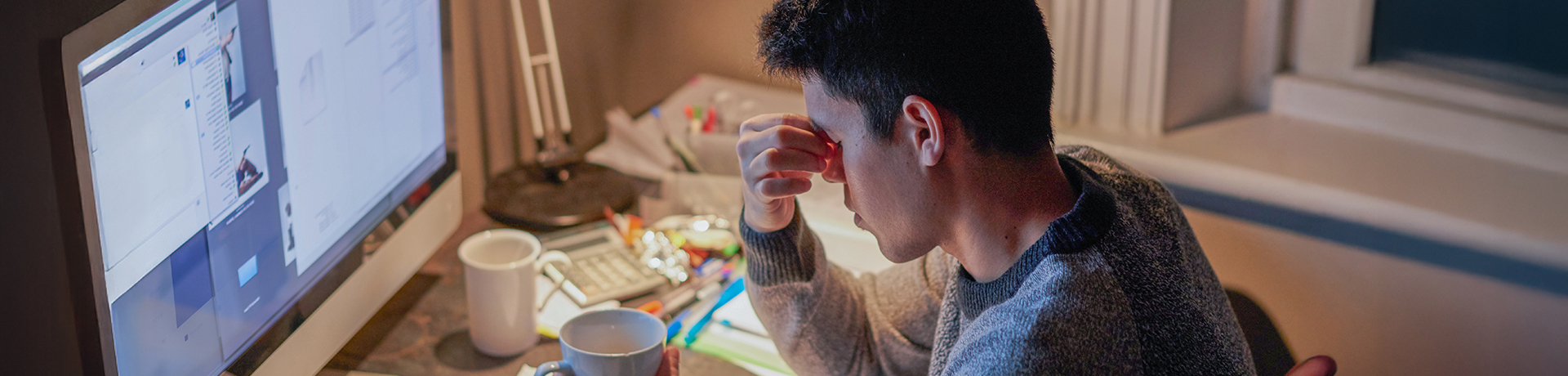 Student hält sich den Kopf beim Lernen am Schreibtisch