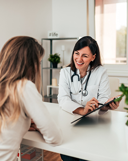 Junge Frau spricht mit einer lächelnden Ärztin