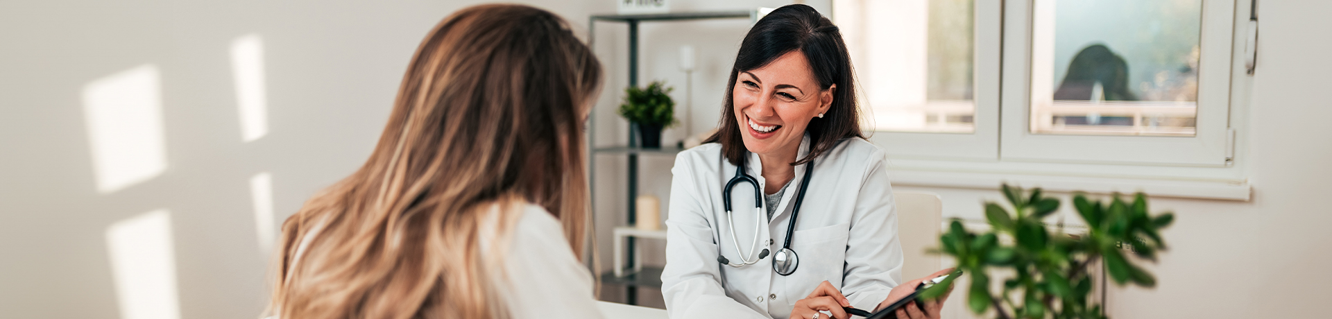 Junge Frau spricht mit einer lächelnden Ärztin