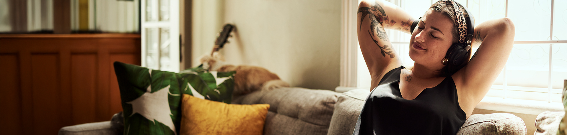 Junge Frau entspannt mit Kopfhörern zurückgelehnt auf einer Couch