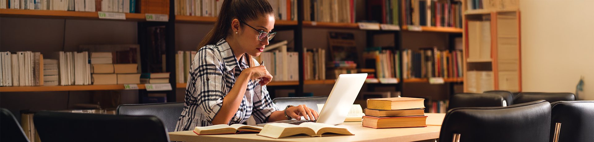 Studentin in einer Bibliothek vor ihrem Laptop