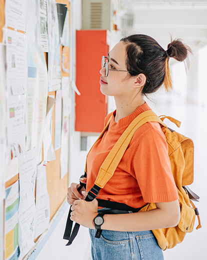 Junge Frau mit Rucksack vor einem Whiteboard