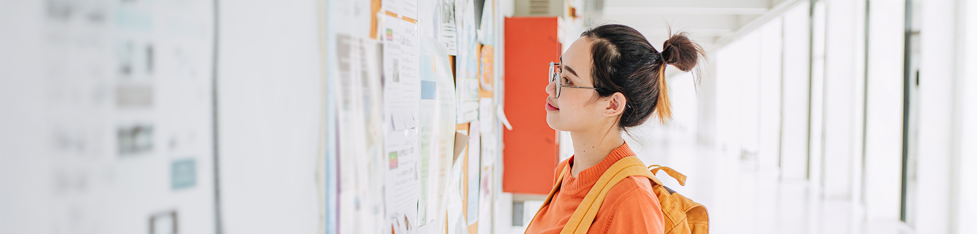 Junge Frau mit Rucksack vor einem Whiteboard