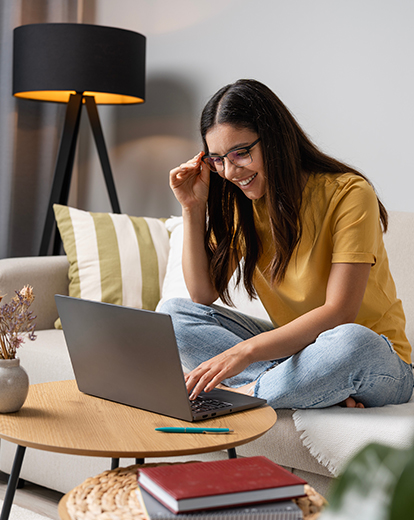 Junge Frau lachend vor einem Laptop