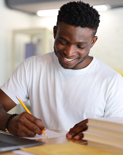 Student lächelnd schreibt auf Papier